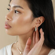 Model Looking to Side Wearing Mint Green Organic Resin Hoop Earrings in Gold with Hand on Ear