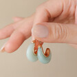 Model Holding Mint Green Organic Resin Hoop Earrings in Gold Between Fingers