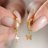 Model Holding Mismatched Star and Lightning Huggie Hoop Earrings in Gold 