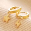 Mismatched Star and Lightning Huggie Hoop Earrings in Gold on Beige Coloured Fabric