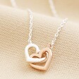 Mixed Metal Tiny Interlocking Hearts Necklace in Silver Close Up on Beige Fabric