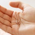 Model holding Mixed Metal Tiny Interlocking Hearts Necklace in Silver in palm of hand