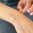 Opal Turtle Charm Bracelet in Gold on model holding chain between fingers