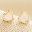 Close Up of Rose Quartz Heart Stud Earrings in Gold on Beige Coloured Fabric