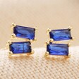 Sapphire Blue Stone Stud Earrings in Gold on Neutral Fabric