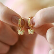 Model Holding Textured Butterfly Huggie Hoop Earrings in Gold Between Fingers