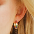 Close Up of Wide Rainbow Crystal Hoop Earrings in Gold on Model