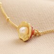 Close up of Underside of Pearl and Enamel Toadstool Anklet in Gold on Beige Ribbed Fabric