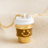 Close up of Smiley Coffee Cup Pendant Necklace in Gold on beige fabric