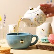 Model Pouring Tea From Cornflower Blue Floral Ceramic Teapot into Mug