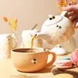 Model Pouring Tea From Teapot Into Mug of Dusky Pink Floral Ceramic Teapot and Mug Set