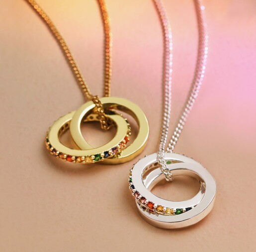 Rainbow Pride Eternity Pendant Necklaces on pink surface with rainbow lighting