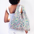 Model in white top wearing the Kind Bag Meadow Flowers Reusable Shopping Bag on shoulder