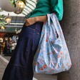 Model wearing the Kind Bag Golden Lily Reusable Shopping Bag on arm