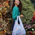 Model in green jumper wearing the Kind Bag Golden Lily Reusable Shopping Bag on arm