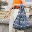 Model in orange top using Kind Bag William Morris Strawberry Thief Reusable Shopping Bag