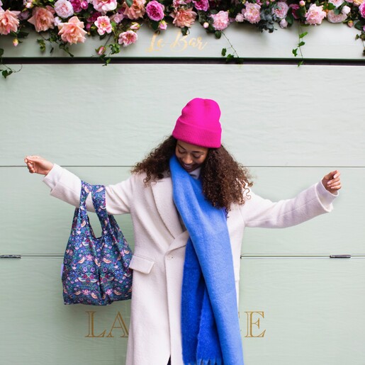 Model in blue scarf and pink hat wearing Kind Bag William Morris Strawberry Thief Reusable Shopping Bag