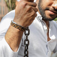 Male model wearing Men's Antiqued Leather Bracelet in Brown with beaded bracelets while holding swing chain
