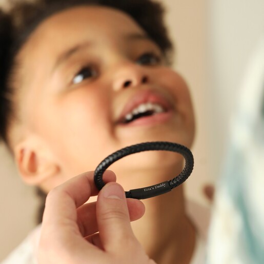 model holding Men's Personalised Leather Bracelet with Matte Black Clasp with child in background
