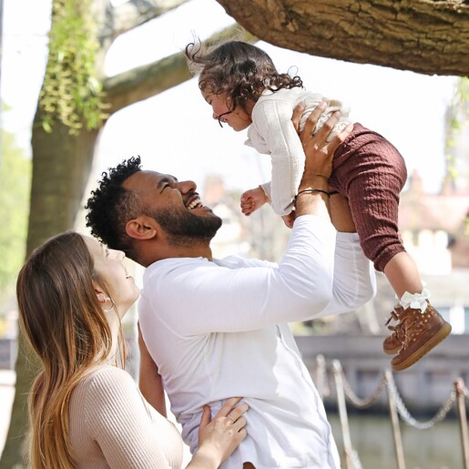 Model Smiling wearing Men's Thin Woven Leather Bracelet in Black holding daughter in the air