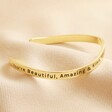 First Side of Adjustable All Things Lovely Meaningful Word Wave Bangle in Gold on neutral fabric