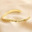 second side of Adjustable All Things Lovely Meaningful Word Wave Bangle in Gold on neutral fabric