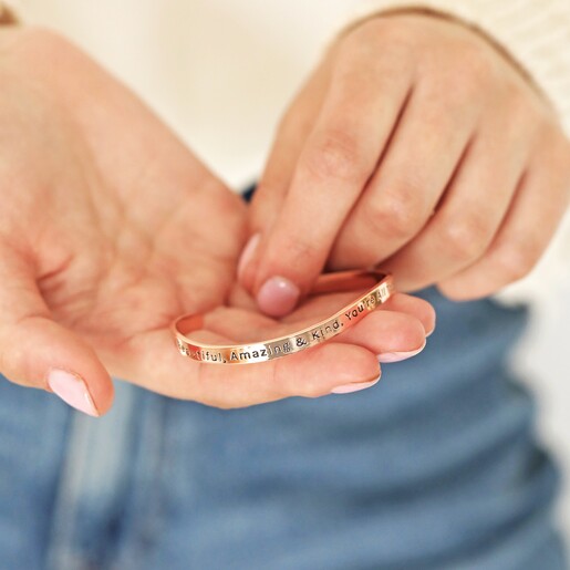 Model holding Adjustable 'All Things Lovely' Meaningful Word Wave Bangle in Rose Gold in palm of hand