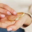 Model holding Adjustable 'Favourite Person' Meaningful Word Wave Bangle in Gold in palm of hand