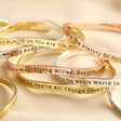 Adjustable Meaningful Word Bangles all stacked together on beige fabric