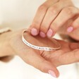 Model holding Adjustable 'Mum' Meaningful Word Wave Bangle in Silver in palm of hand