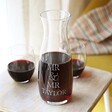 Personalised Couples Crystal Carafe with Mr & Mr Taylor personalisation in lifestyle shot with wine and two wine tumblers
