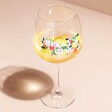 Personalised Floral Fruit Balloon Gin Glass with liquid inside on neutral coloured background