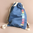 Personalised Rainbow Name BagBase Denim Drawstring Bag on natural coloured background