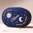 Personalised Sun and Moon Embroidered Oval Jewellery Case in Navy on its Side on a Neutral Coloured Background