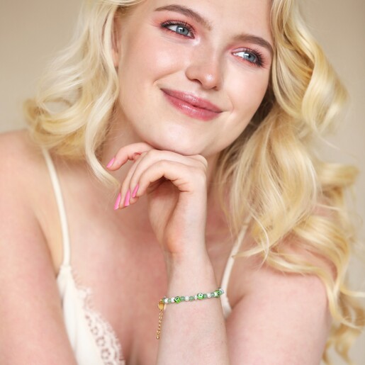 Model smiling looking to side wearing Green Millefiori Flower Beaded Bracelet in Gold