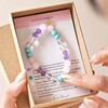 Close Up of Model Holding Positive Energy Semi-Precious Stone Beaded Bracelet in Pink With Information Card in Box