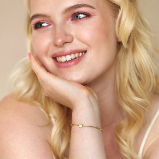 Model looking to side wearing Smiling Heart Face and Enamel Ball Chain Bracelet in Gold with hand on cheek
