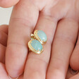model holding Blue Oval Semi-Precious Stone Stud Earrings in Gold between fingers