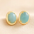 Blue Oval Semi-Precious Stone Stud Earrings in Gold on neutral coloured fabric