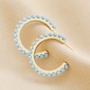 Blue Stone Hoop Earrings in Gold on Beige Coloured Material