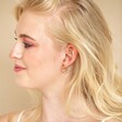 Side profile of blonde model wearing the Colourful Enamel Pom Pom Huggie Hoop Earrings in Gold