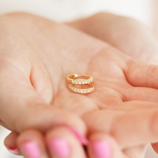 Model Holding Hoops Crystal Huggie Hoops in Gold in models hands