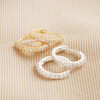 Crystal Huggie Hoops in Silver and Gold on Beige Fabric