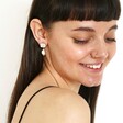 Smiling female model wearing Crystal Stud and Freshwater Pearl Drop Earrings in Gold