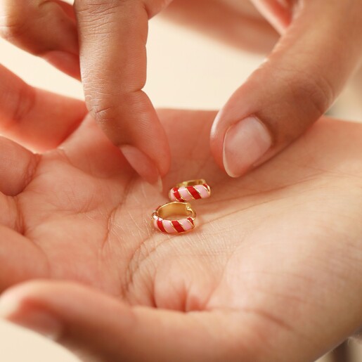 Model Holding Enamel Striped Huggie Hoop Earrings in Red and Pink