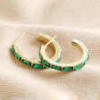 Green Baguette Crystal Hoop Earrings in Gold on neutral coloured fabric