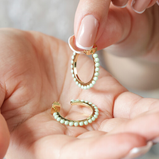 Model Holding Green Stone Hoop Earrings in Gold in Palm of Hand