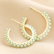 Green Stone Hoop Earrings in Gold on Neutral Coloured Fabric