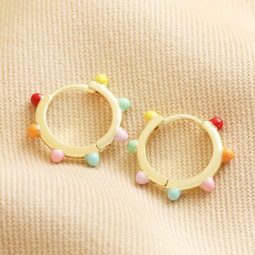 Enamel Pom Pom Huggie Hoop Earrings in Gold Flat Lay on beige fabric