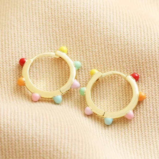 Enamel Pom Pom Huggie Hoop Earrings in Gold Flat Lay on beige fabric